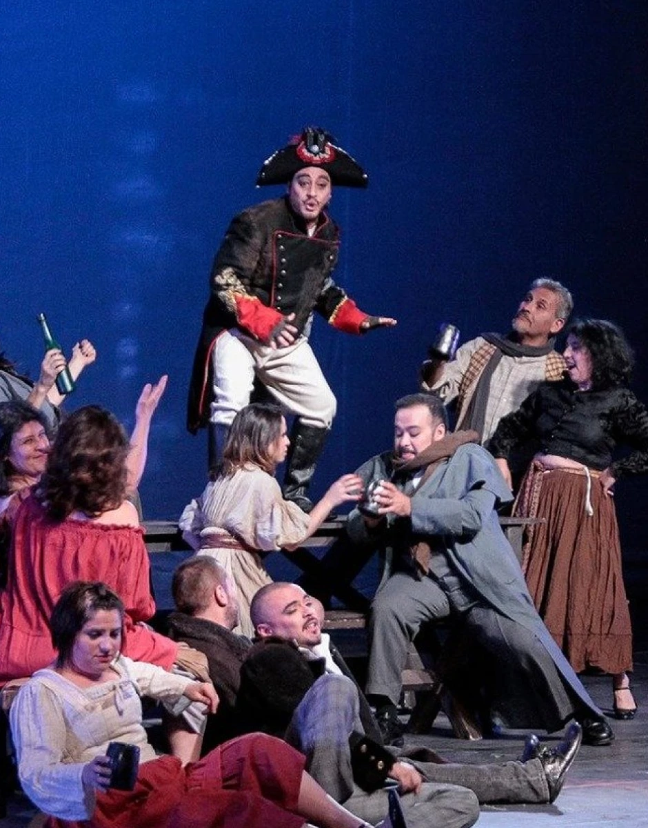 Photographie d’un spectacle mettant en scène plusieurs comédiens en costumes sur une scène de théâtre.